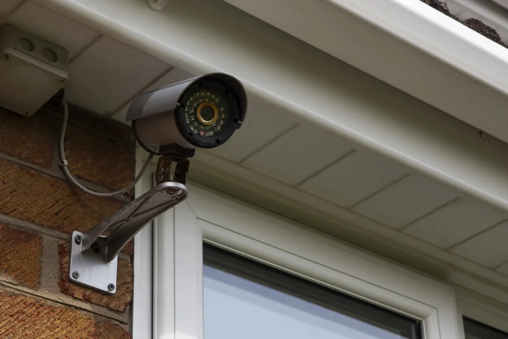 Et overvågningskamera som er monteret på et hus ved siden af vinduet.