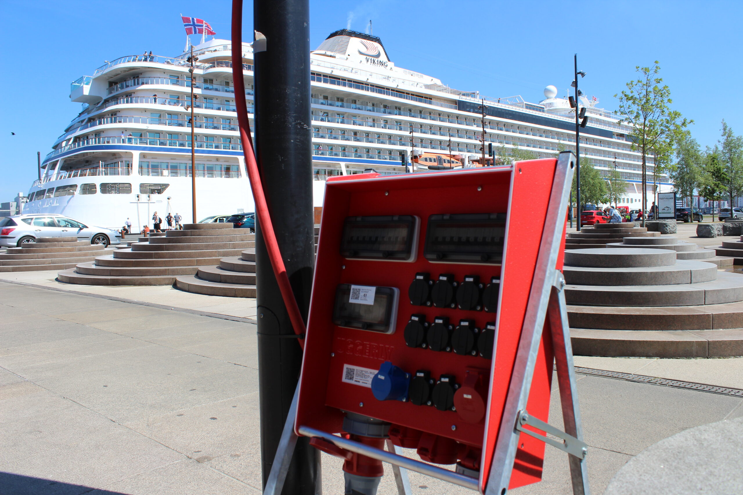 Elektriker som udfører el-tjek Byggestrømstavle på havnen foran et krydstogtskib.